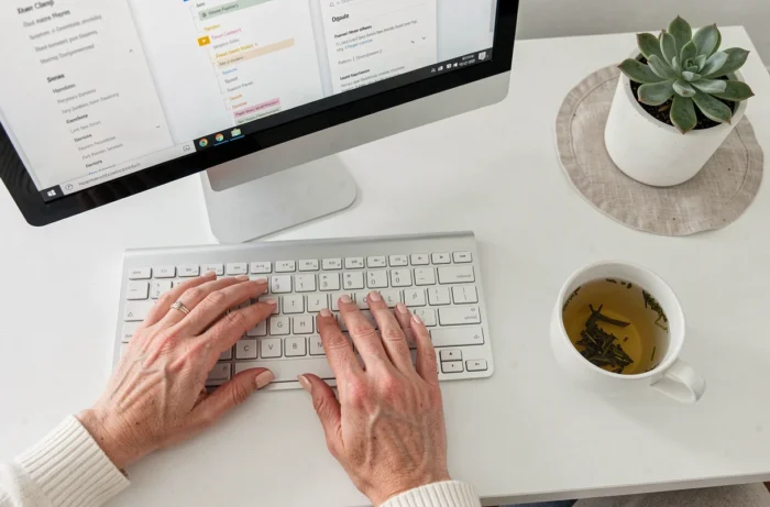 Gros plan de mains féminines naviguant sur un plan de site web depuis un bureau minimaliste